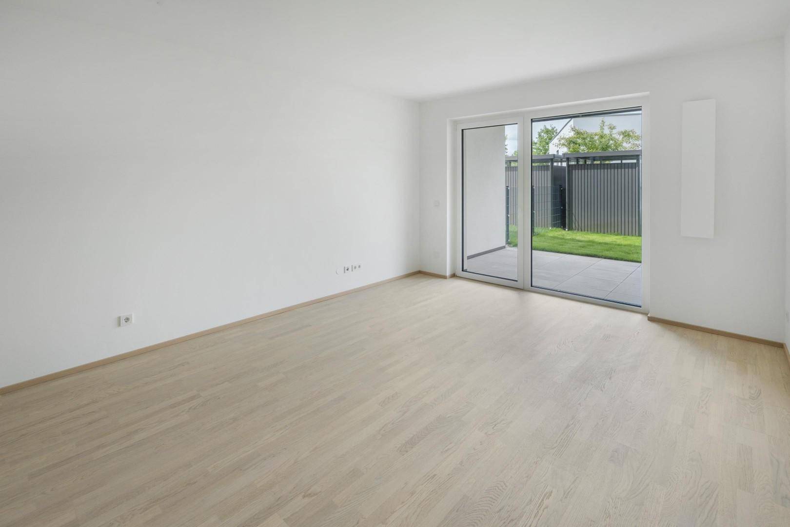Helles Zimmer mit modernem Holzboden und direktem Zugang zur Terrasse und zum Garten.