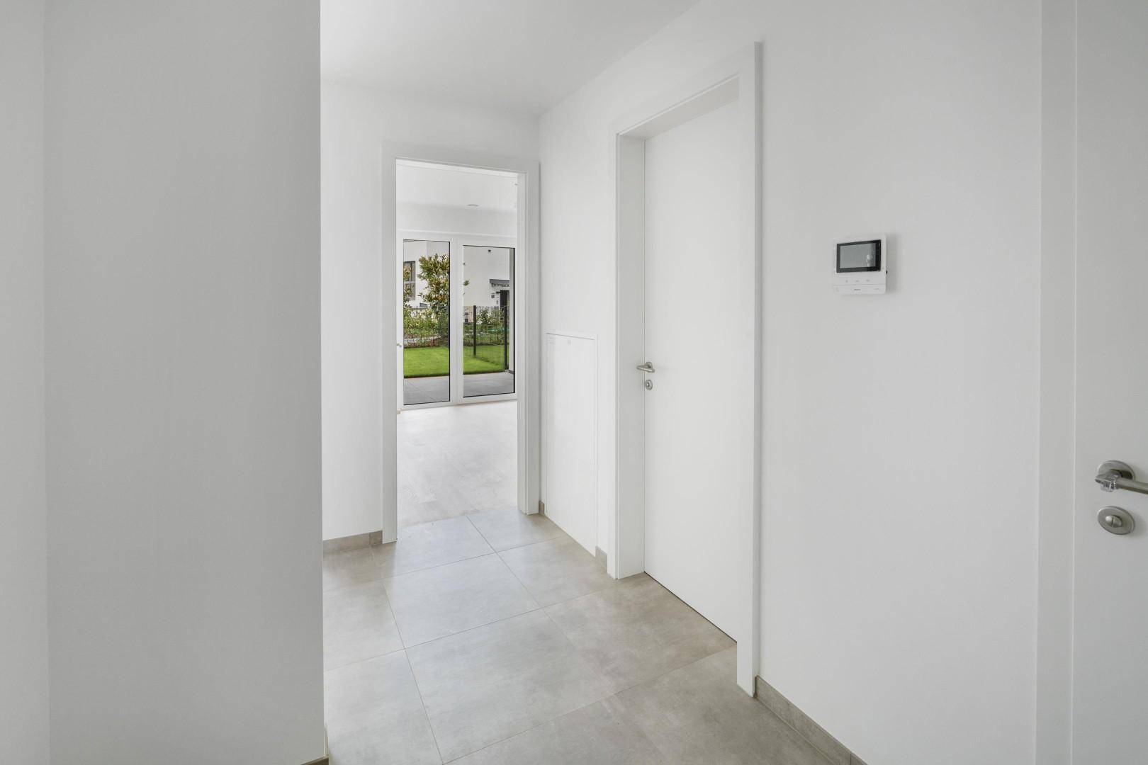 Heller Flur mit modernen Fliesen und Zugang zu weiteren Räumen und dem Garten.