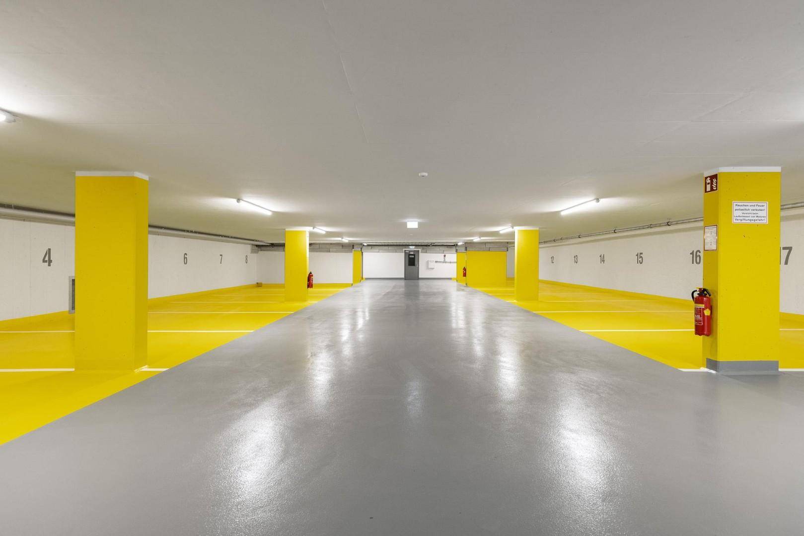 Weitläufige Tiefgarage mit vielen Stellplätzen und klarer Markierung auf dem Boden.