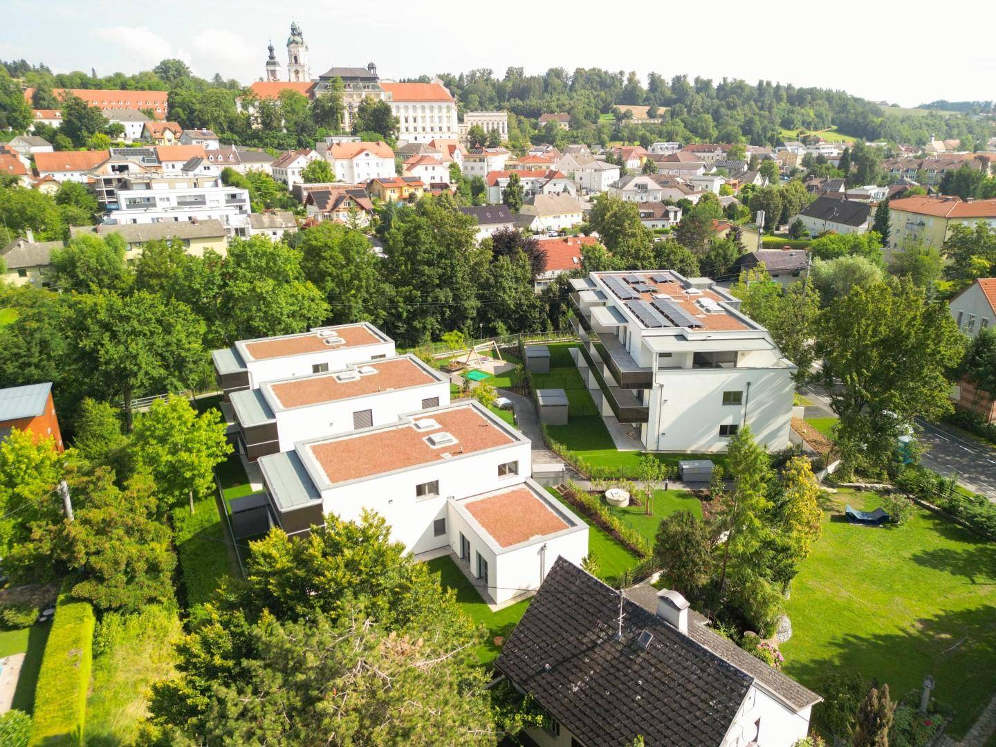 Luftaufnahme einer modernen Wohnanlage mit mehreren Gebäuden und grünen Außenbereichen.