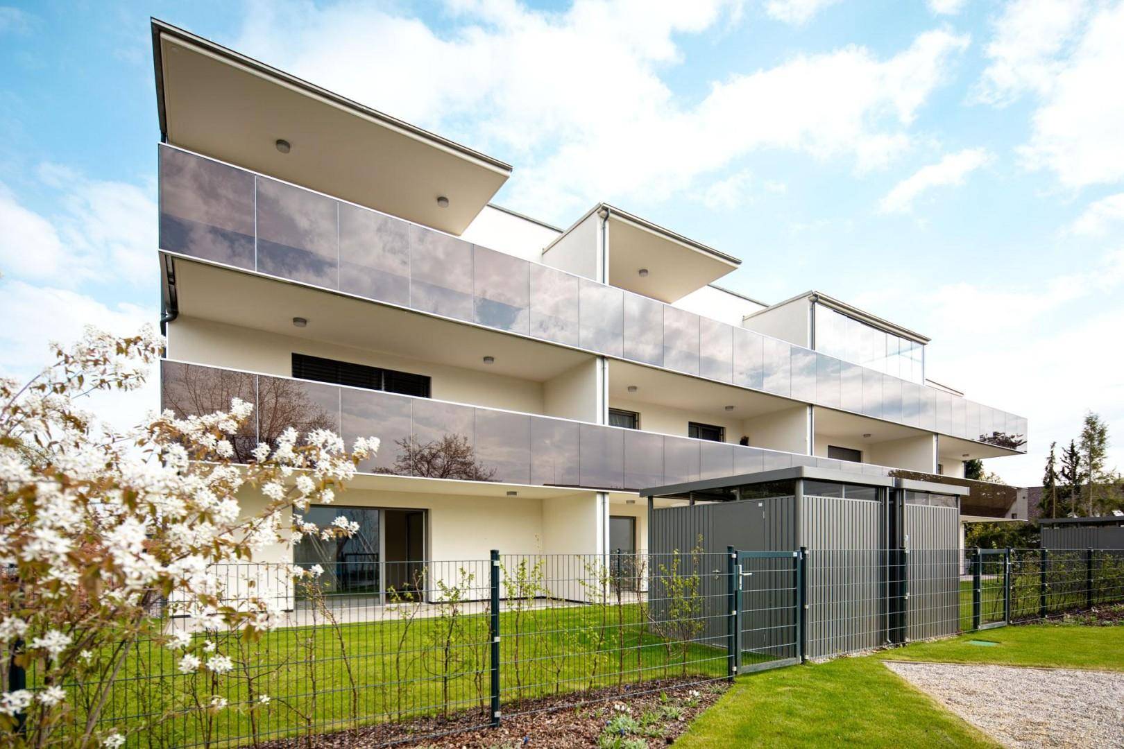Neubau-Wohnanlage mit moderner Architektur, Balkonen und gepflegten Grünflächen im Vordergrund.