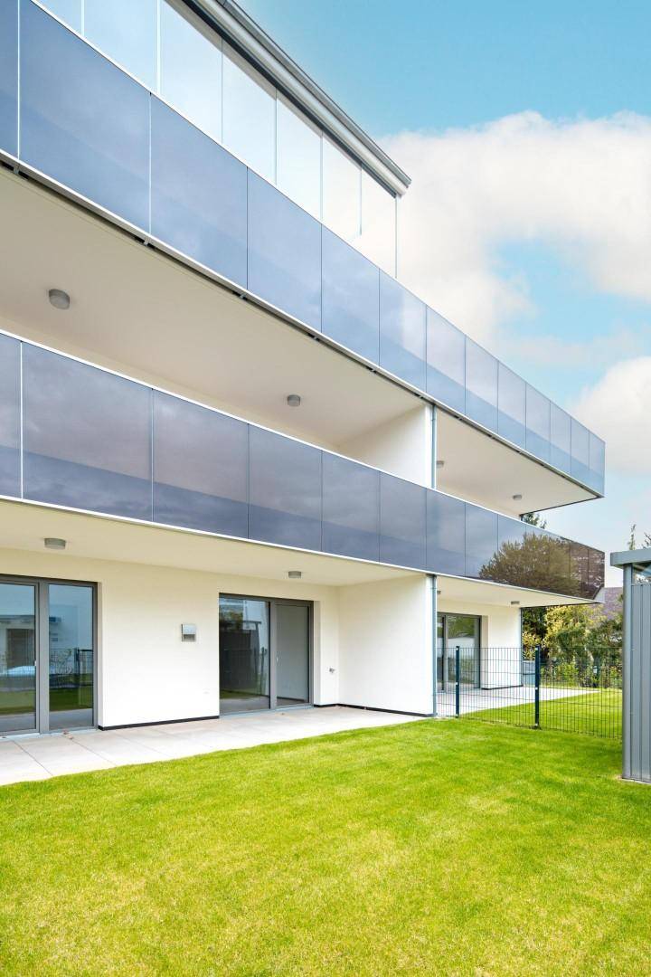Ansicht eines modernen Wohngebäudes mit mehreren Etagen, Balkonen und großen Fensterfronten.