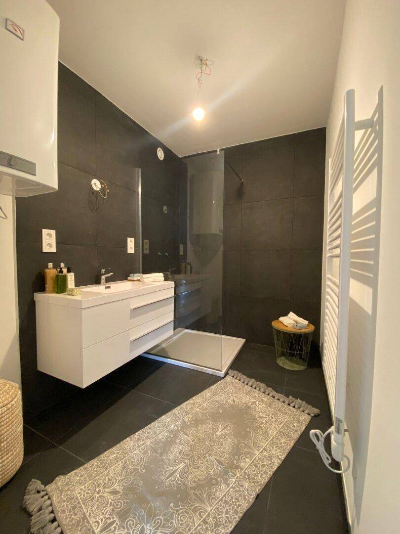 Modernes Badezimmer mit dunklen Fliesen, begehbarer Dusche und Handtuchheizkörper.