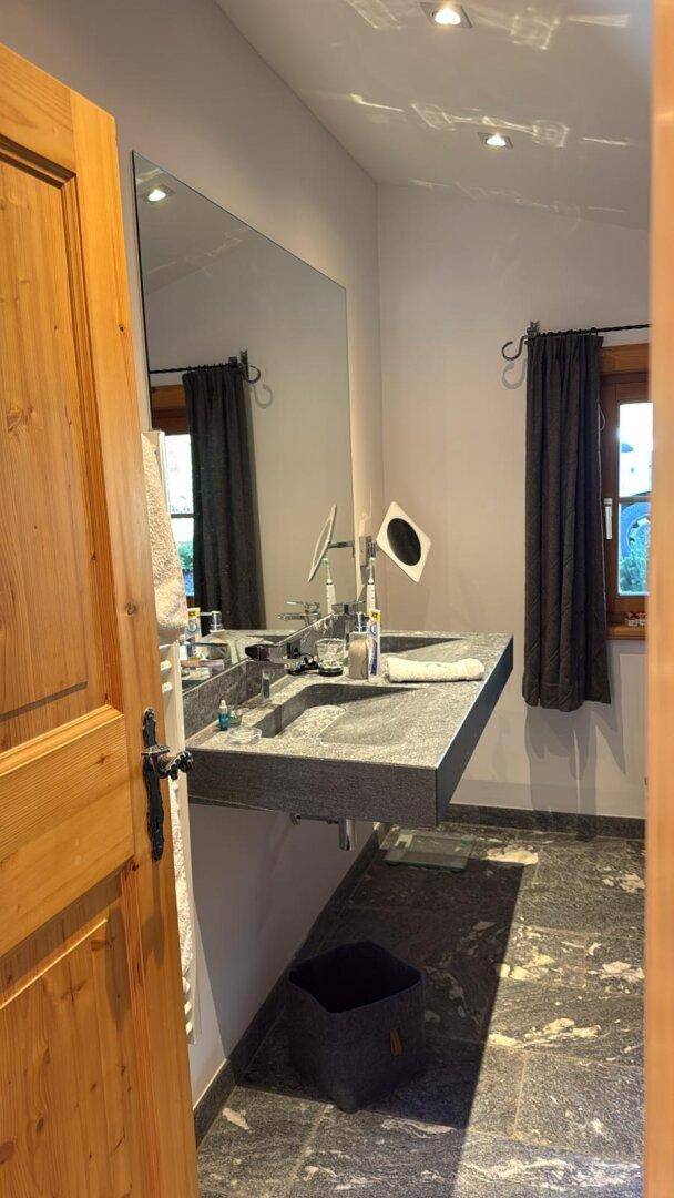 Elegantes Badezimmer mit schwebendem Doppelwaschtisch aus Stein und großem Spiegel.