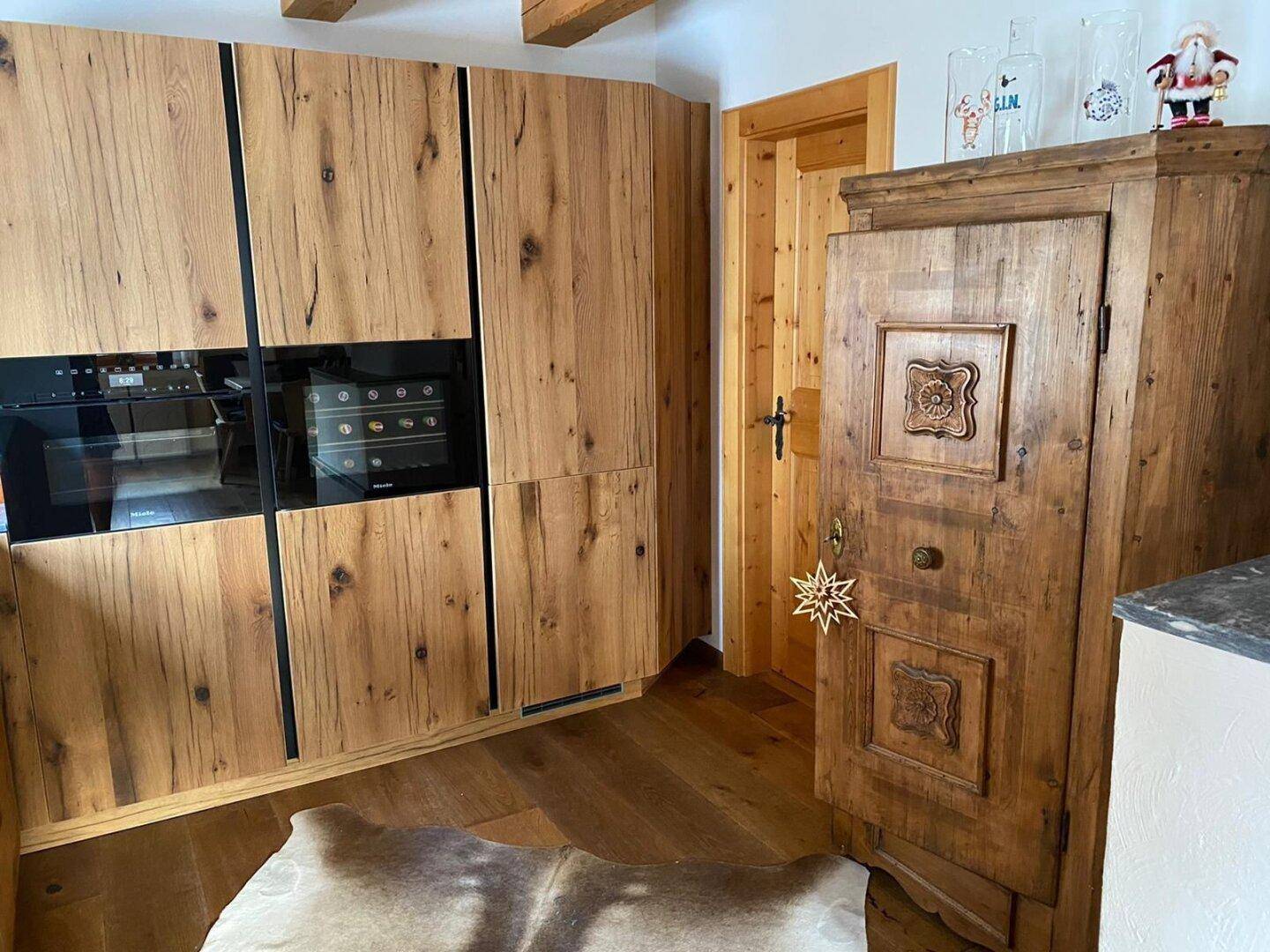 Hochwertige Holzküche mit integrierten Miele-Geräten und traditionellem Bauernschrank.