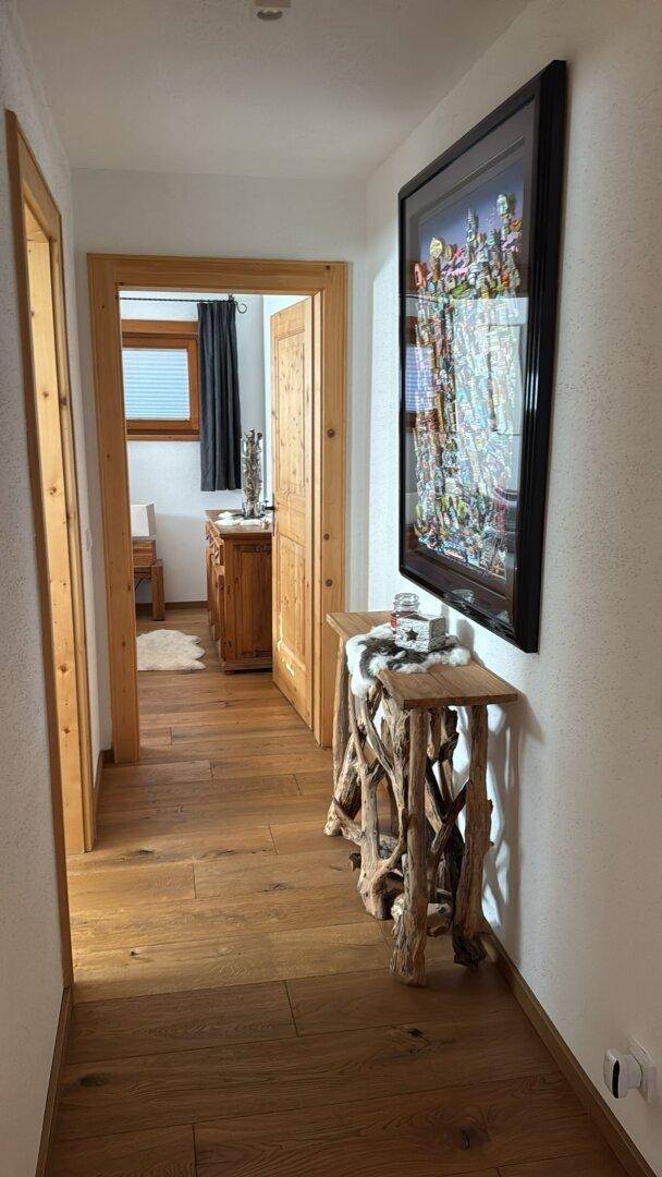 Heller Flur mit Holzboden und rustikalem Konsolentisch, der zu weiteren Räumen führt.