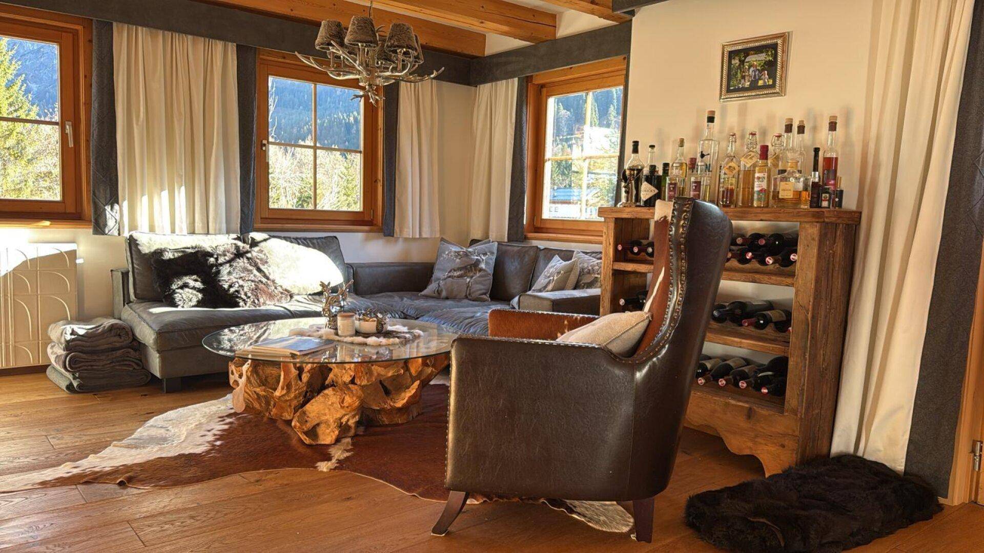 Gemütliches Wohnzimmer im alpinen Stil mit großem Sofa, Kamin und Bergblick.