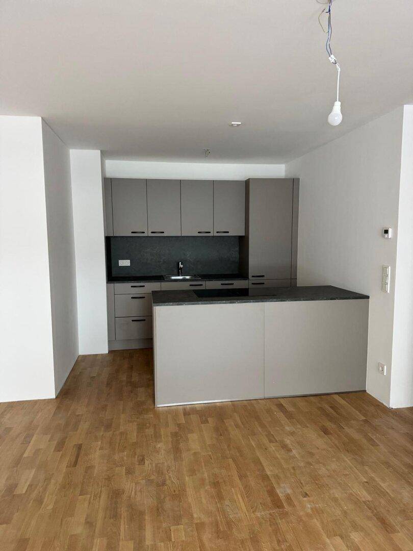 Moderne Küche mit grauen Schränken, dunkler Arbeitsplatte und einer Kücheninsel.
