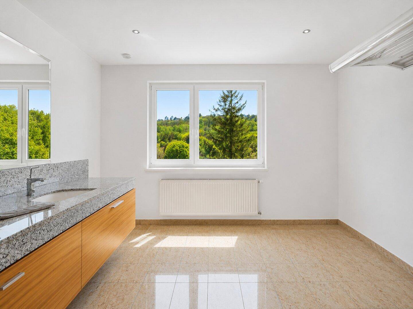 Helles Badezimmer mit Fenster, Doppelwaschbecken mit Granitplatte und hellen Fliesenboden.