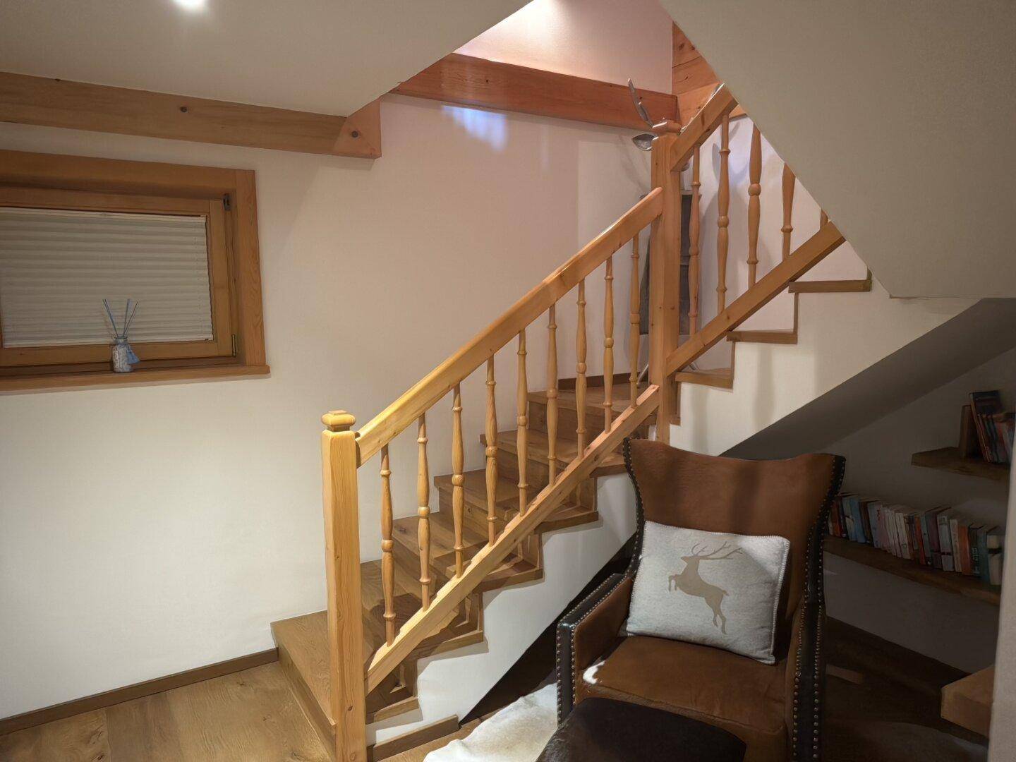 Elegante Holztreppe mit Geländer und Leseecke unter dem Dach.