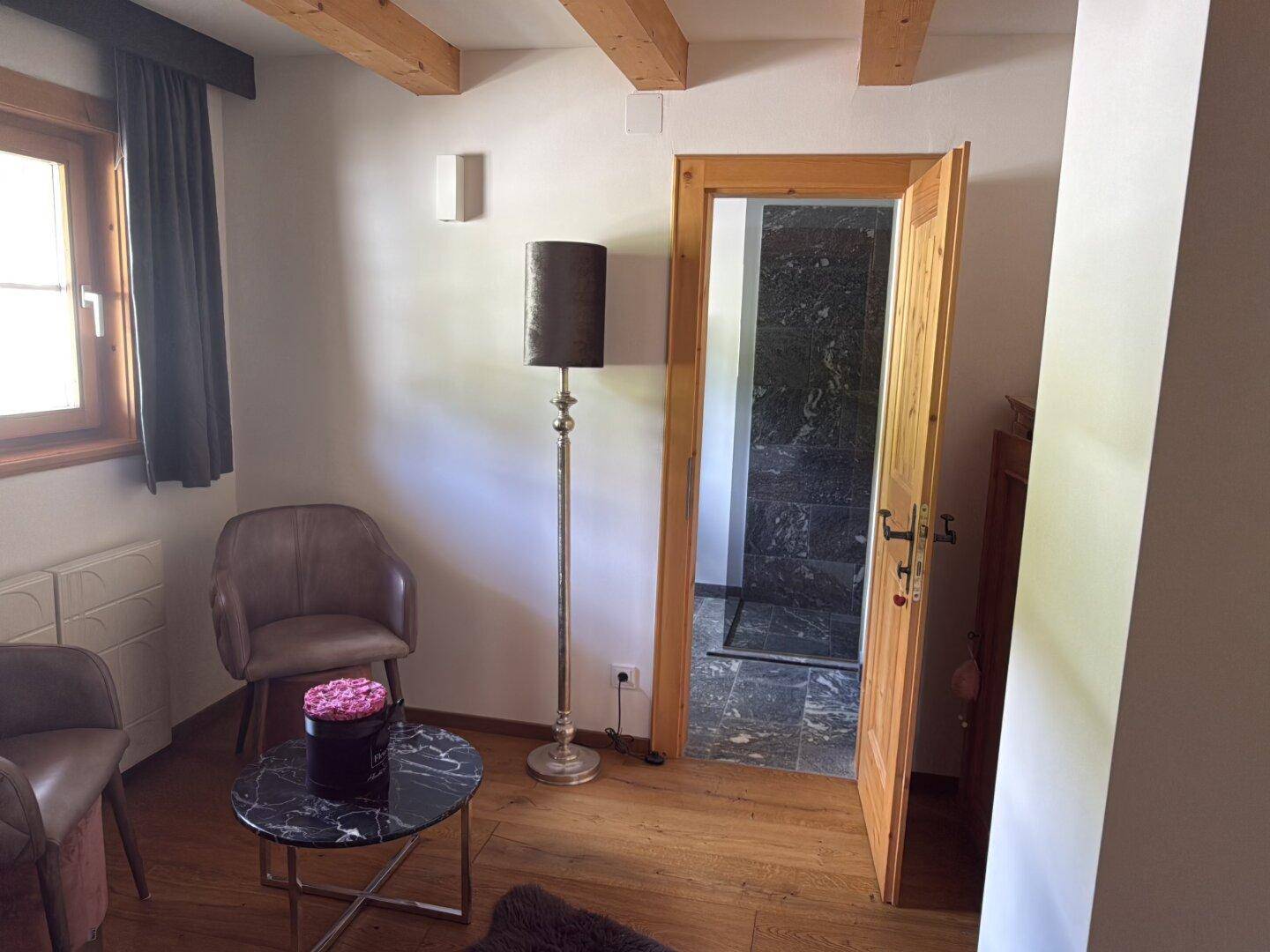 Kleiner Sitzbereich im Flur mit Holzboden und Zugang zu einem Badezimmer.