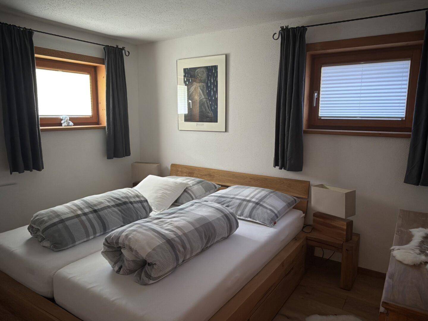 Helles Schlafzimmer mit zwei Einzelbetten, Holzboden und Fenstern für Tageslicht.