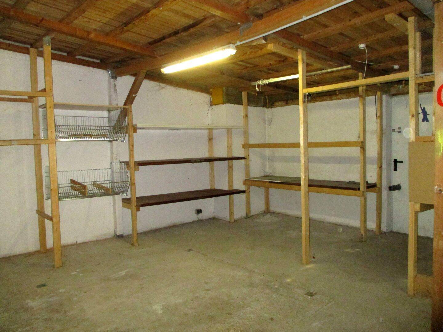 Geräumiger Lagerraum mit robusten Holzregalen, weißen Wänden und einem Betonboden, ideal für Organisation.