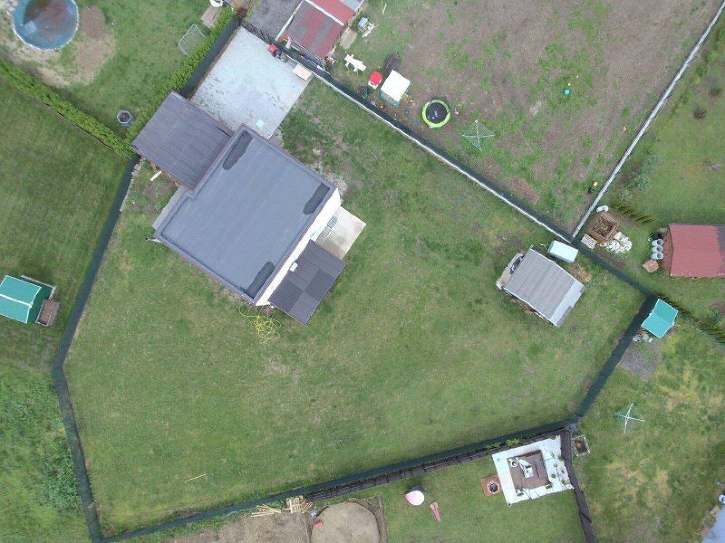 Luftaufnahme des Grundstücks mit Einfamilienhaus, Flachdach und großem Gartenbereich.