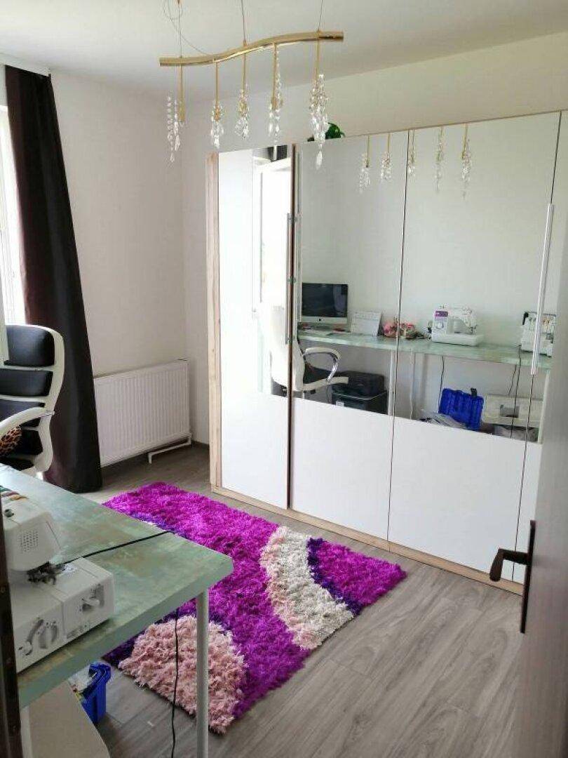 Arbeitszimmer mit Holzoptik-Fliesen, Spiegelschränken und einem farbenfrohen Teppich.