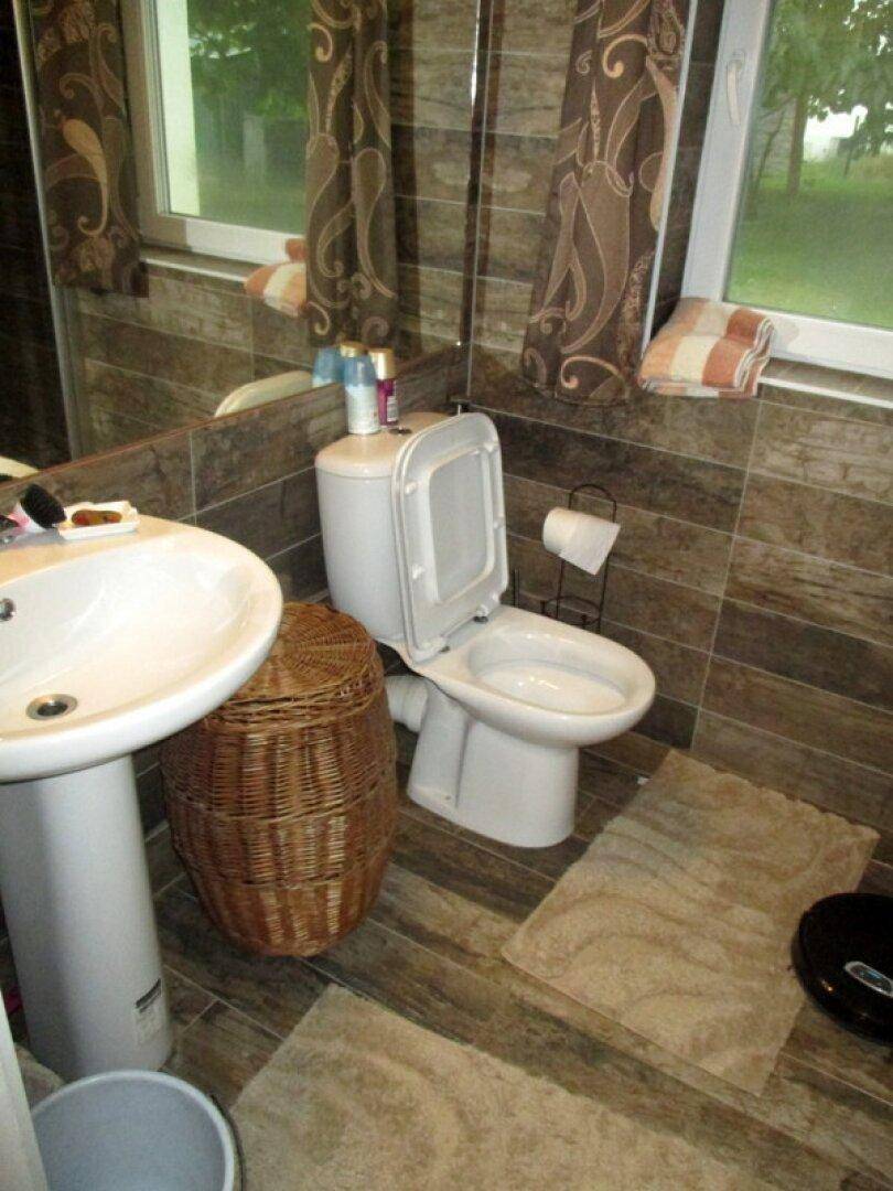 Kleines Badezimmer mit braunen Fliesen, Waschbecken und Toilette.