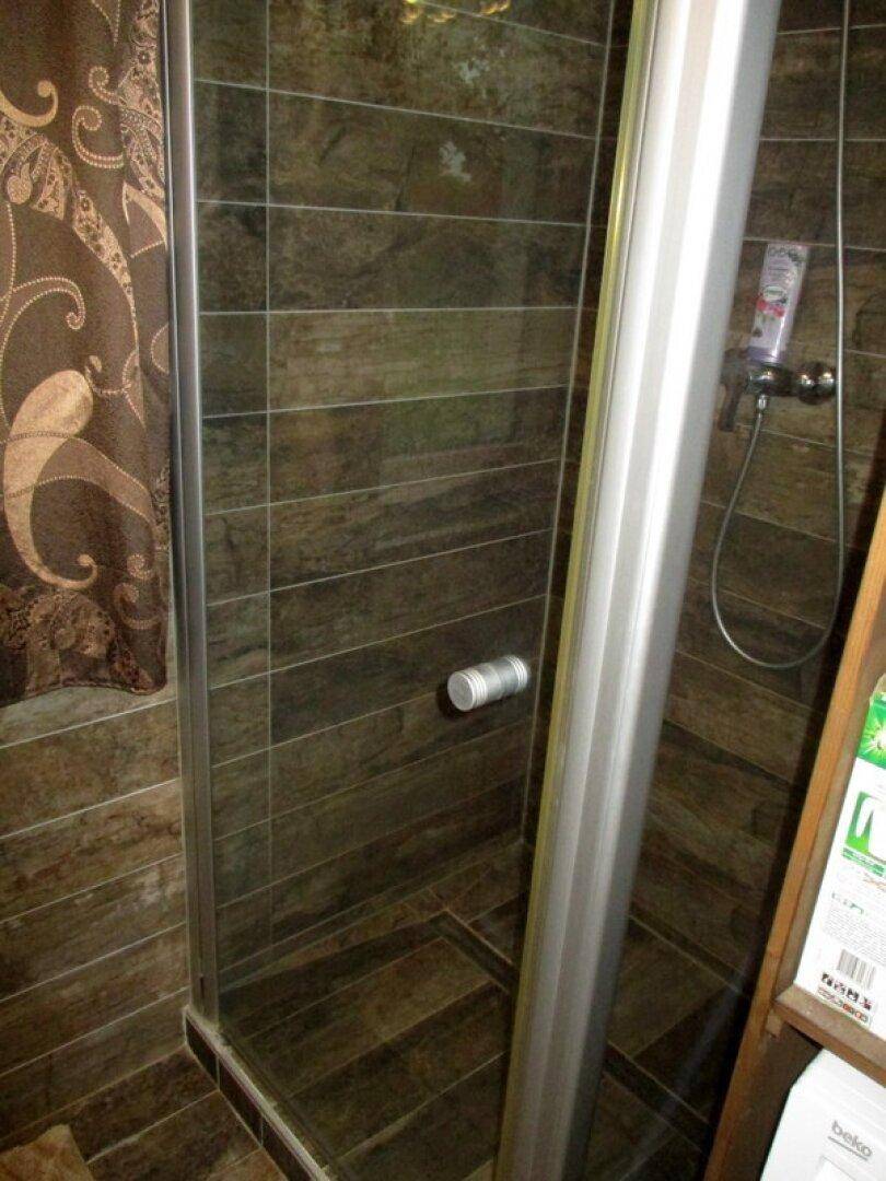Duschkabine mit braunen Fliesen und moderner Armatur in einem Badezimmer.