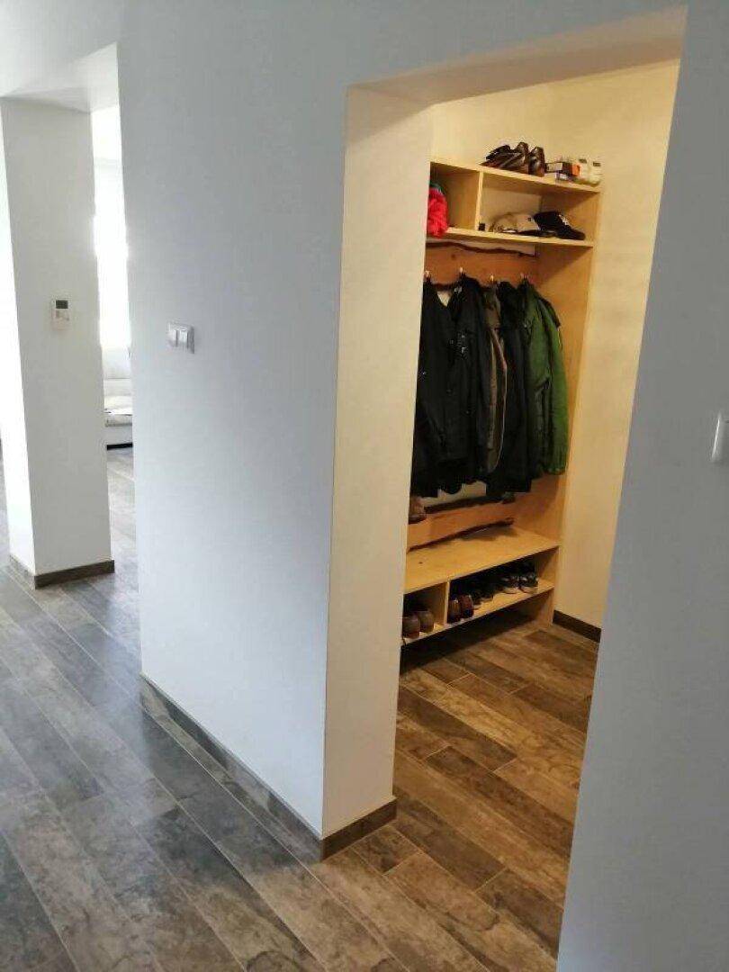 Eingangsbereich mit Holzoptik-Fliesen und integrierten Garderobenschränken für Kleidung und Schuhe.
