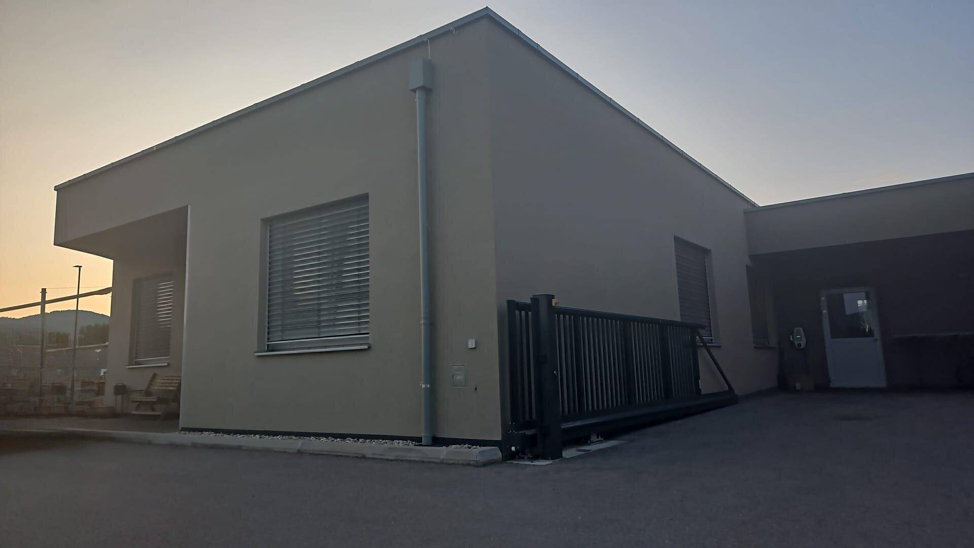 Modernes Geschäftsgebäude mit schlichter Fassade und großen Fenstern bei Sonnenuntergang.