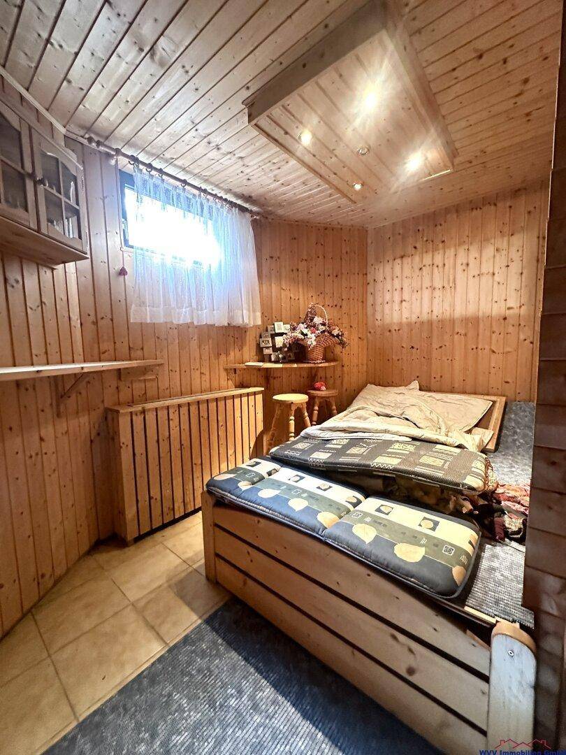 Rustikaler Raum im Untergeschoss mit Holzverkleidung, Fliesenboden und Sitzgelegenheiten.