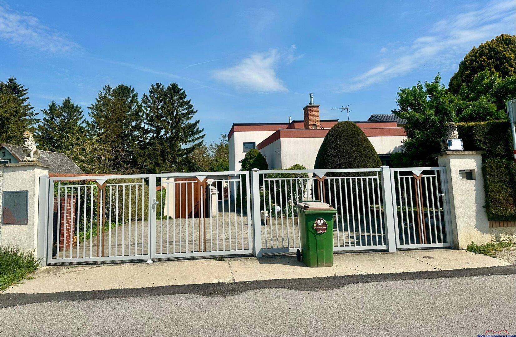 Eingangstor zum Grundstück mit gepflasterter Zufahrt und Blick auf das Haus.