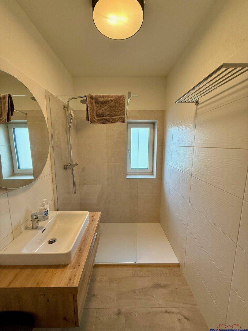 Modernes Badezimmer mit begehbarer Dusche, Holzwaschtisch und hellen Fliesen.