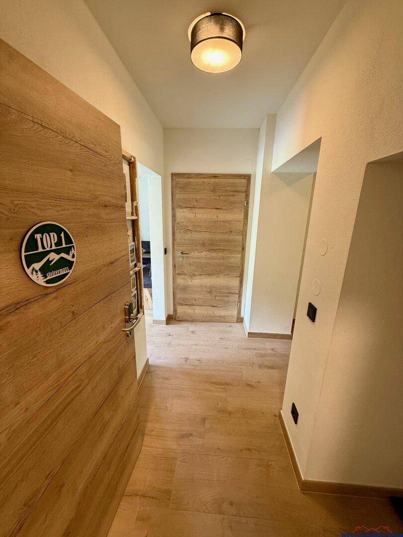 Heller Flur mit Holzboden und Holztüren, der zu den einzelnen Apartments führt.