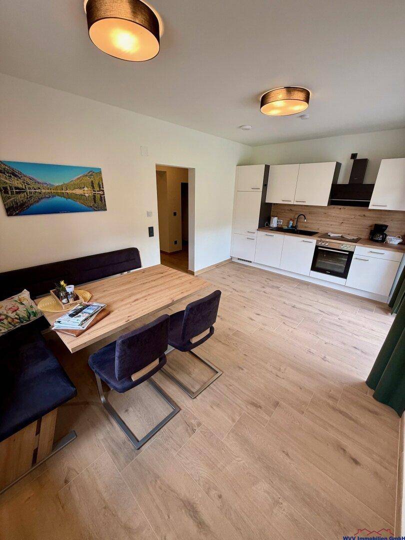 Moderne Einbauküche mit Essbereich, hellen Schränken und Holzboden in offenem Design.