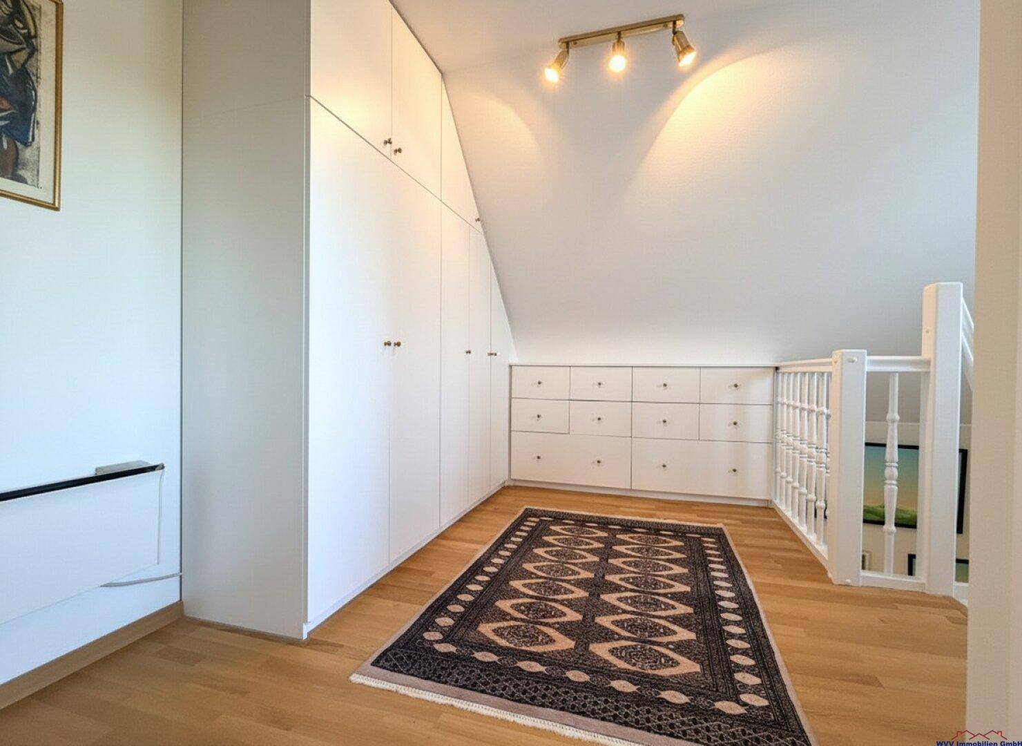 Geräumiger Flur im Dachgeschoss mit Einbauschränken und Holzboden.