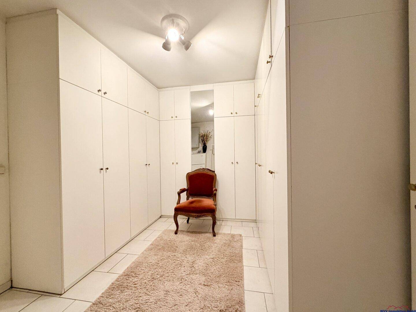 Begehbarer Kleiderschrank mit vielen Einbauschränken und Teppichboden.