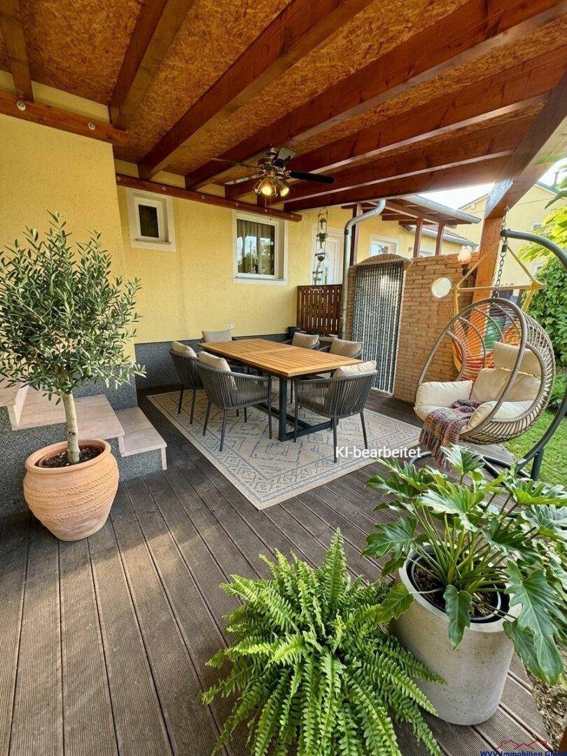 Überdachte Terrasse mit Esstisch, bequemen Stühlen und dekorativen Pflanzen.