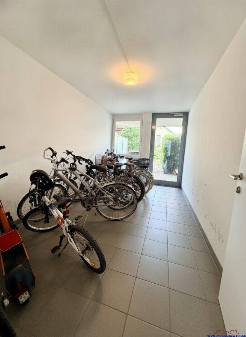Gemeinschaftlicher Fahrradraum mit mehreren Fahrrädern und Zugang nach draußen.