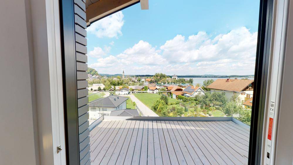 Panoramablick vom Balkon über die Stadt und den See unter blauem Himmel.