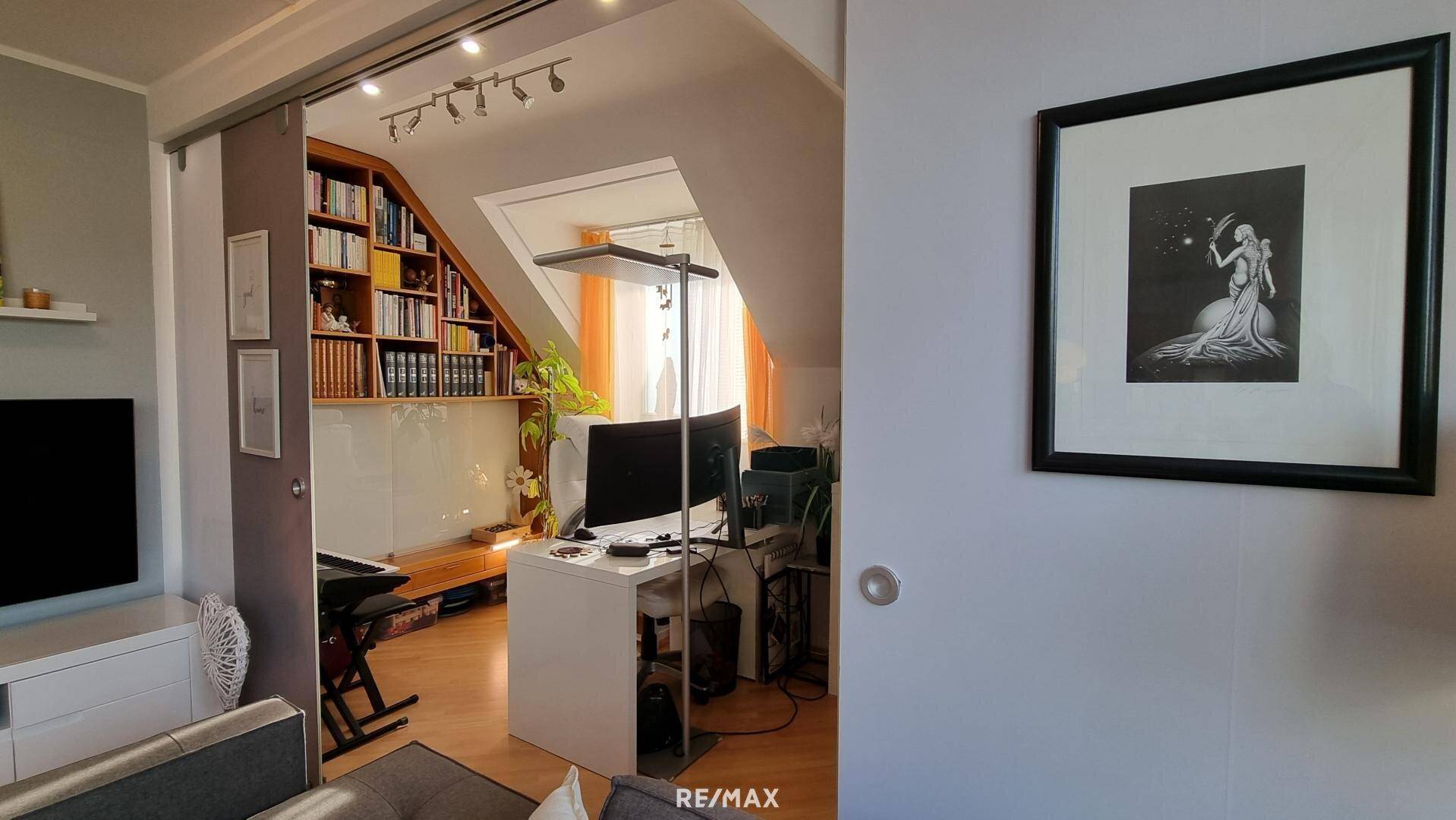 Helles Arbeitszimmer mit Dachschräge, integrierten Bücherregalen und modernem Schreibtischbereich.