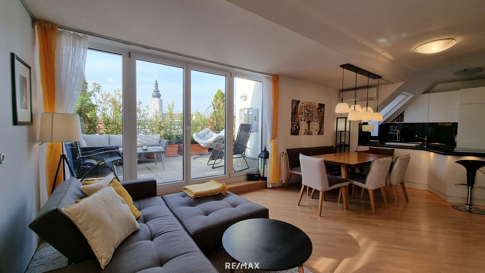 Offener Wohnbereich mit Sofa, Essgruppe und Küche, direktem Zugang zur sonnigen Dachterrasse.