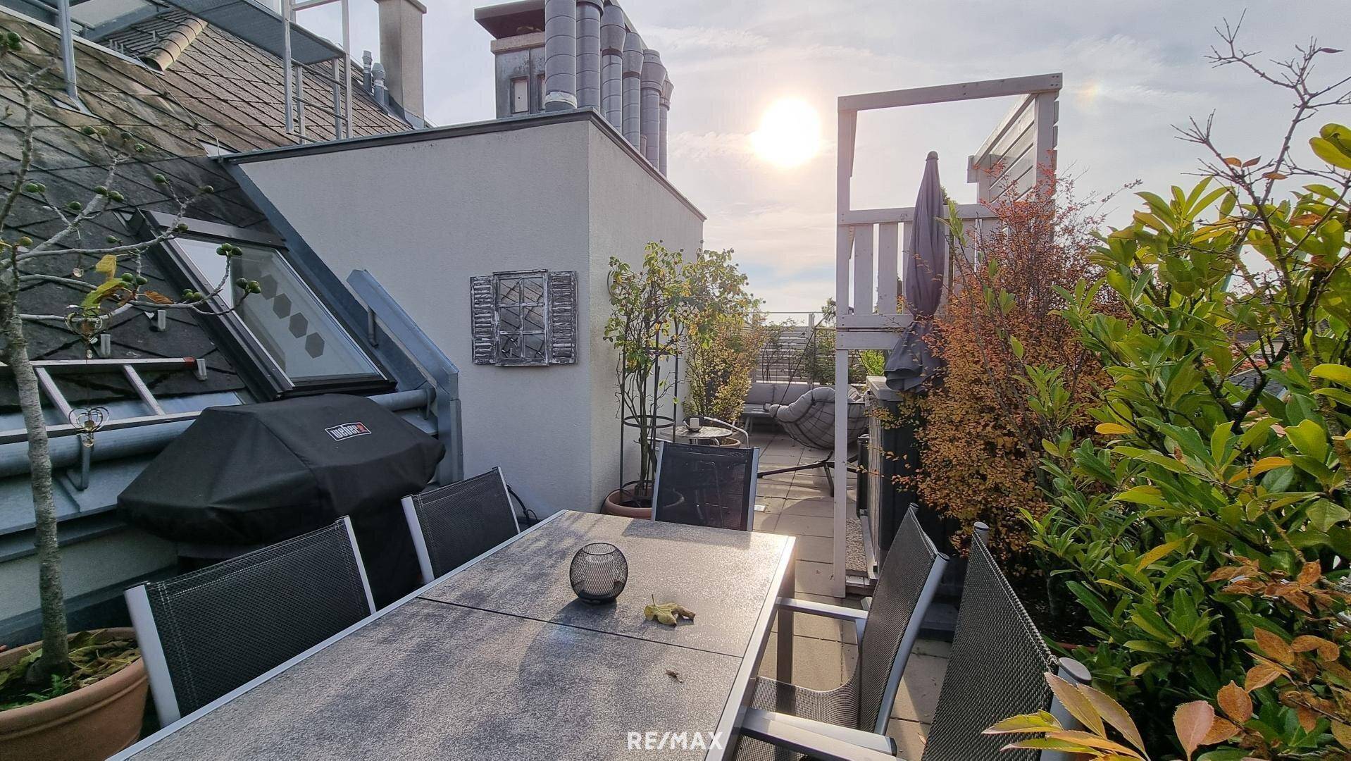 Geräumige Dachterrasse mit Esstisch, Grillbereich und Blick auf die umliegenden Dächer.