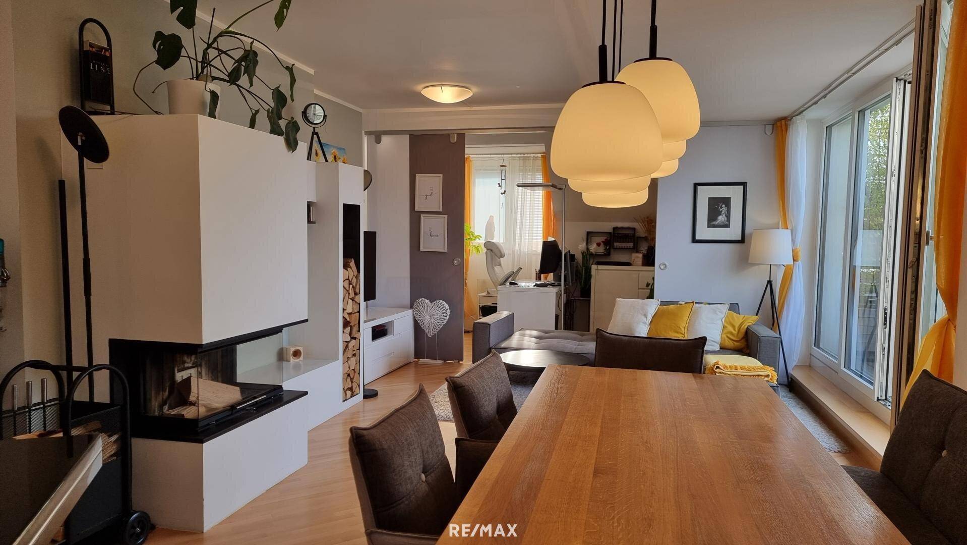 Geräumiger Wohn- und Essbereich mit Kamin, Holzboden und Zugang zu weiteren Räumen.