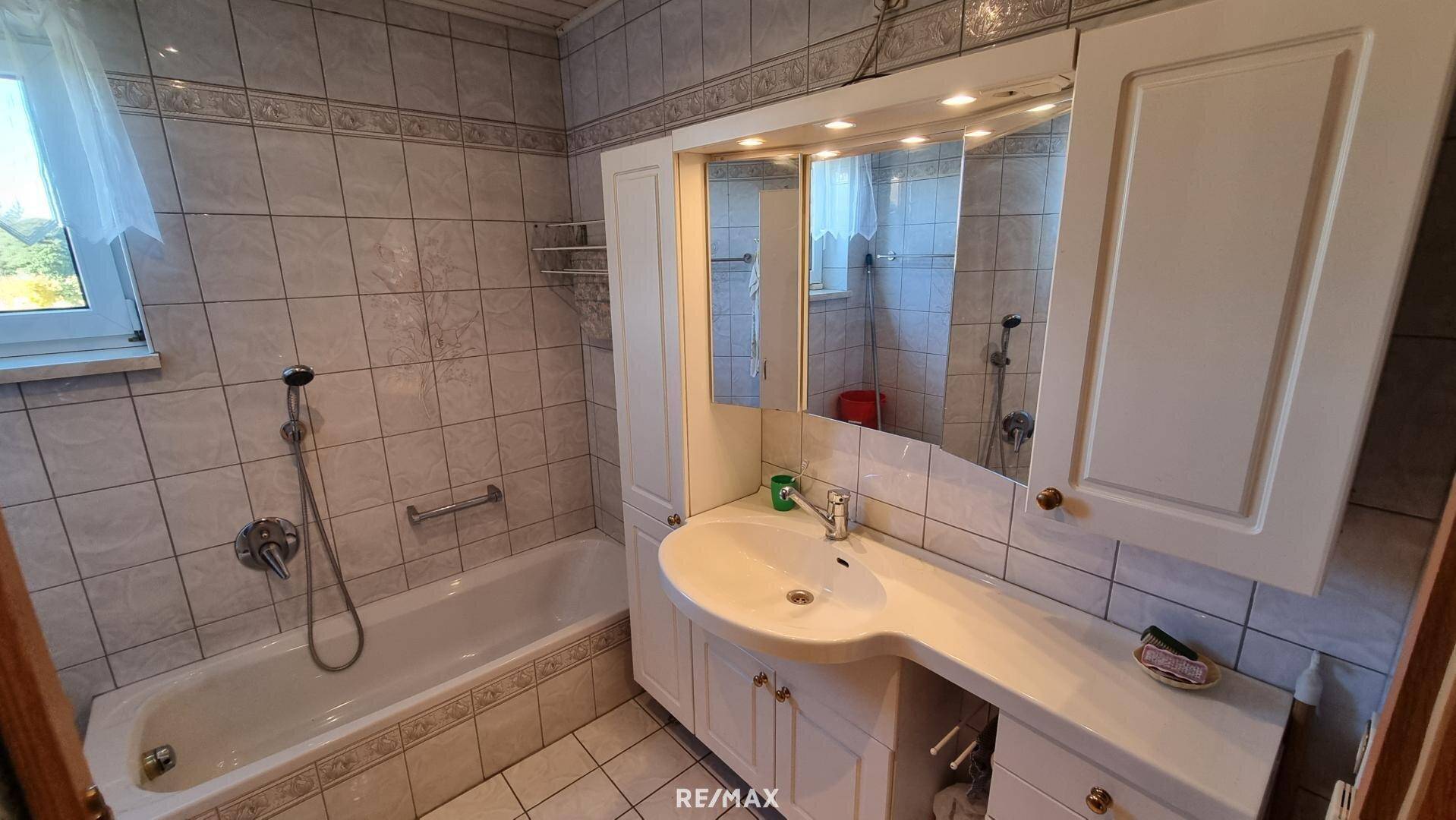 Badezimmer mit Badewanne, Waschtisch und Spiegelschrank.