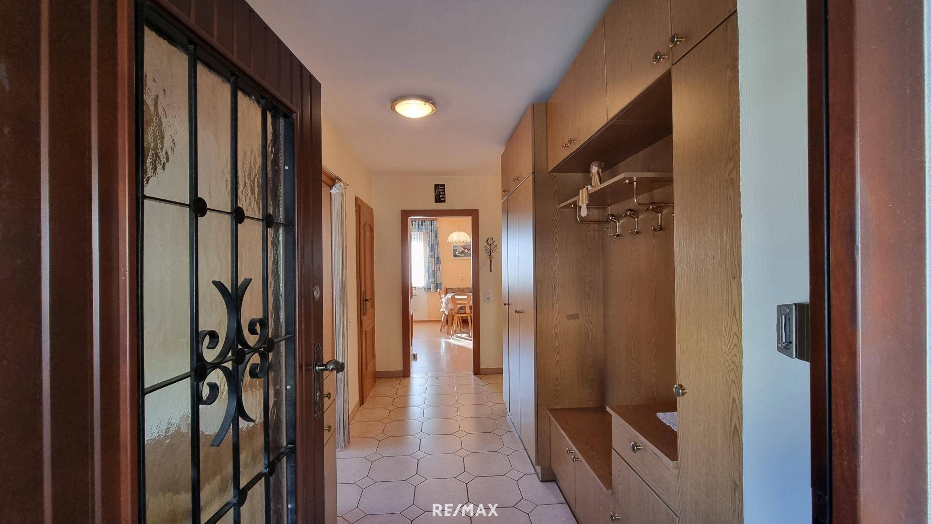 Heller Flur mit Fliesenboden, Garderobe und Zugang zu weiteren Räumen.