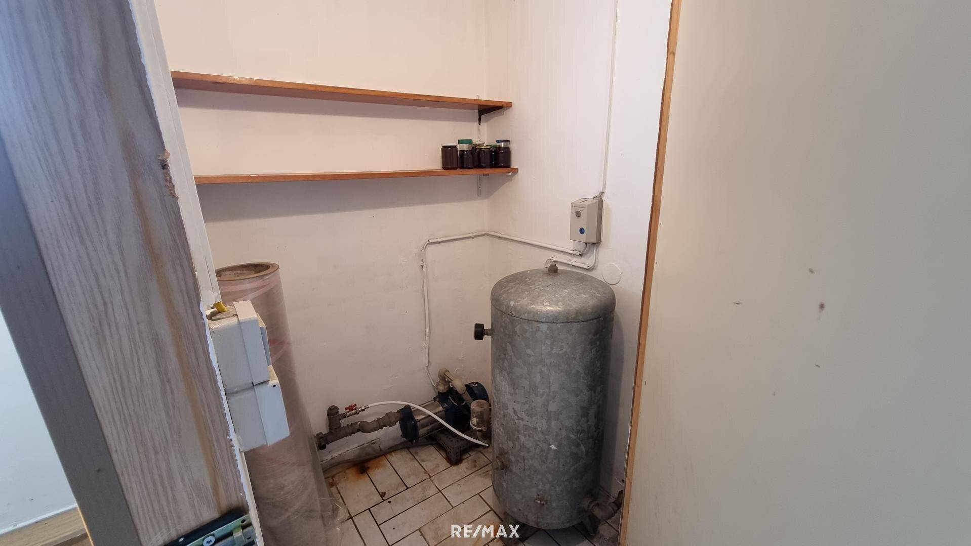 Kellerraum mit Wasserboiler und Regalen für zusätzlichen Stauraum.