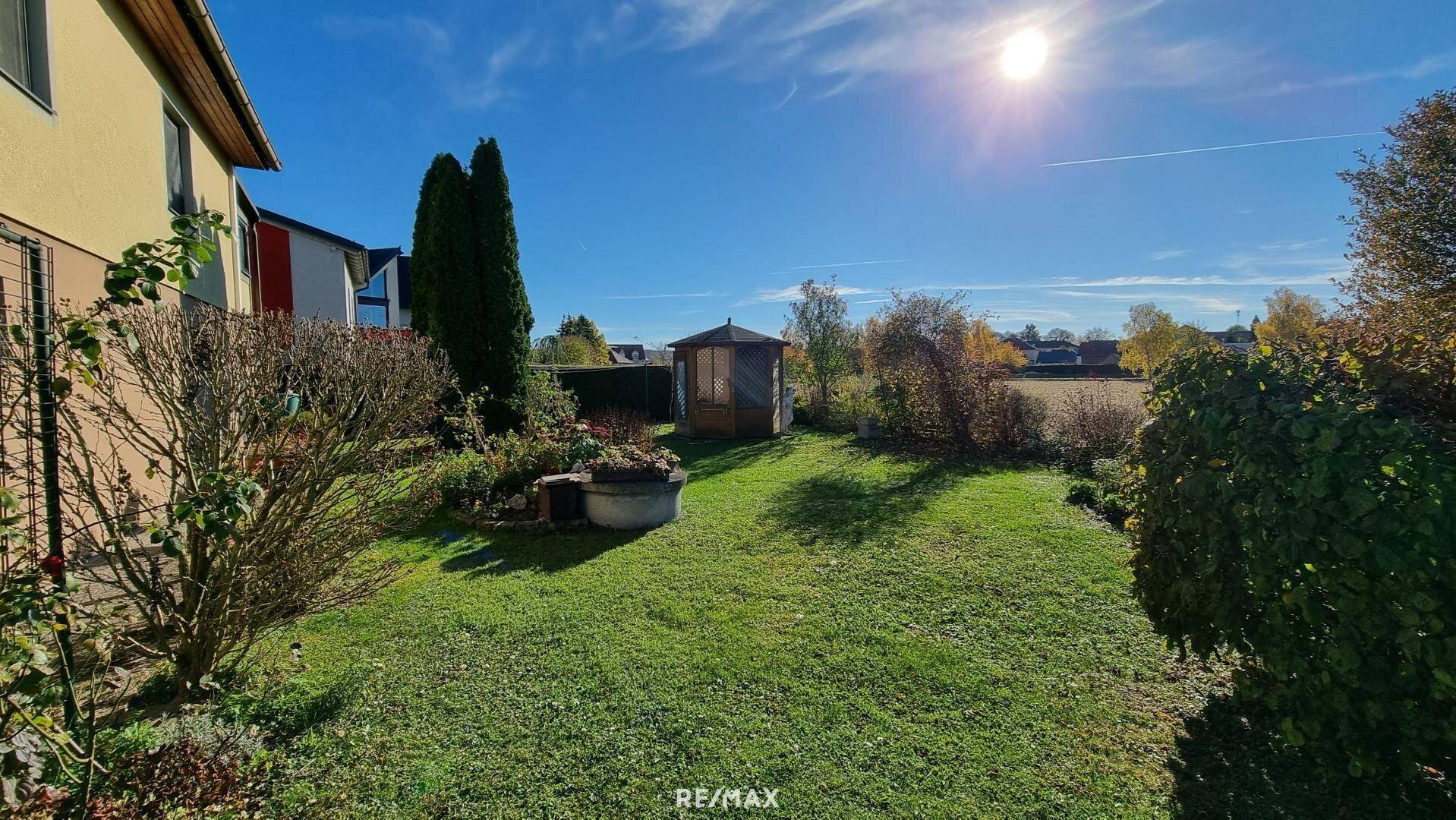 Großer, gepflegter Garten mit Rasenfläche, Bäumen und Gartenlaube.
