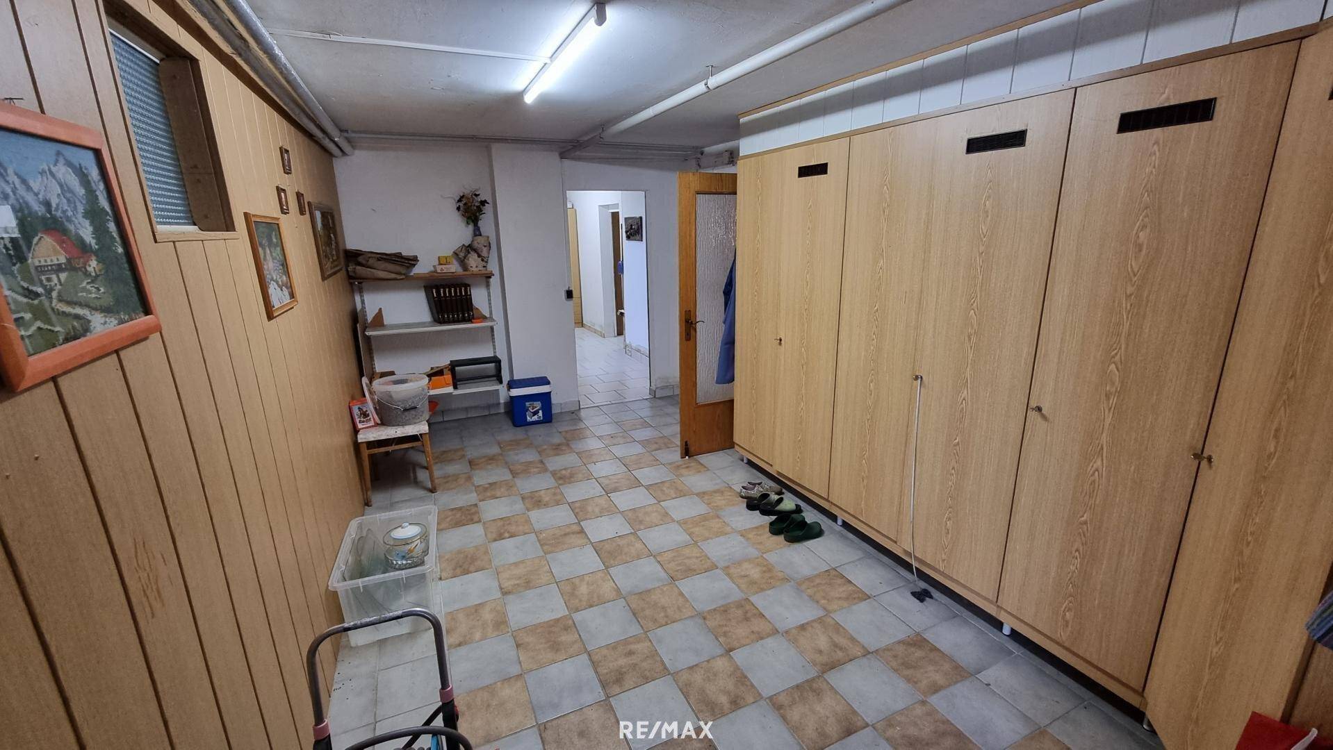 Geräumiger Kellerflur mit Einbauschränken und Fliesenboden.