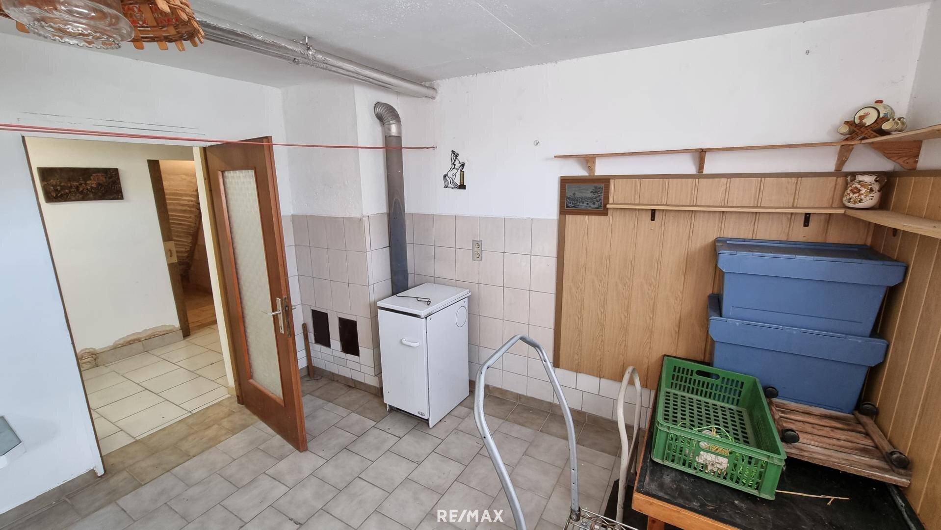 Kellerraum mit Kachelofen, Regalen und Stauraum.