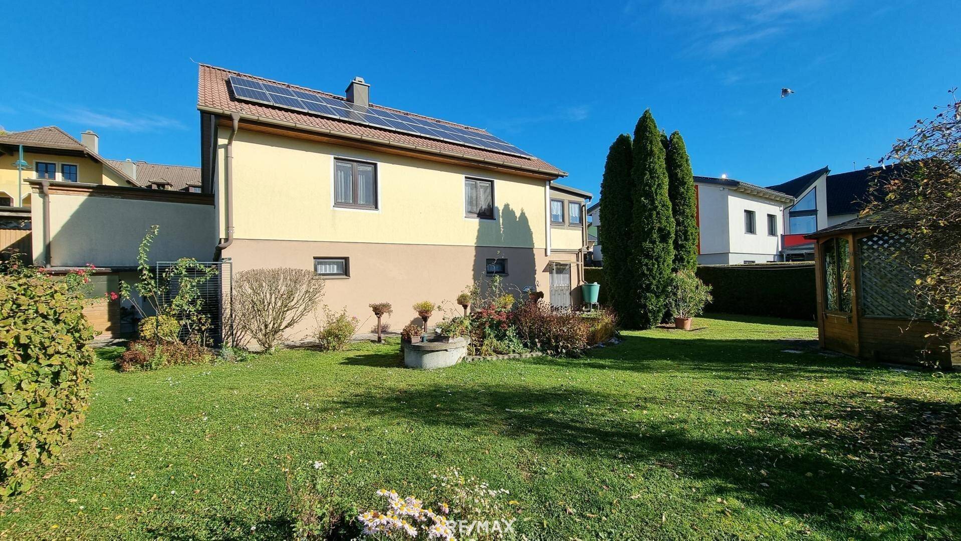 Rückansicht des Hauses mit großem Garten, Photovoltaikanlage und viel Grün.