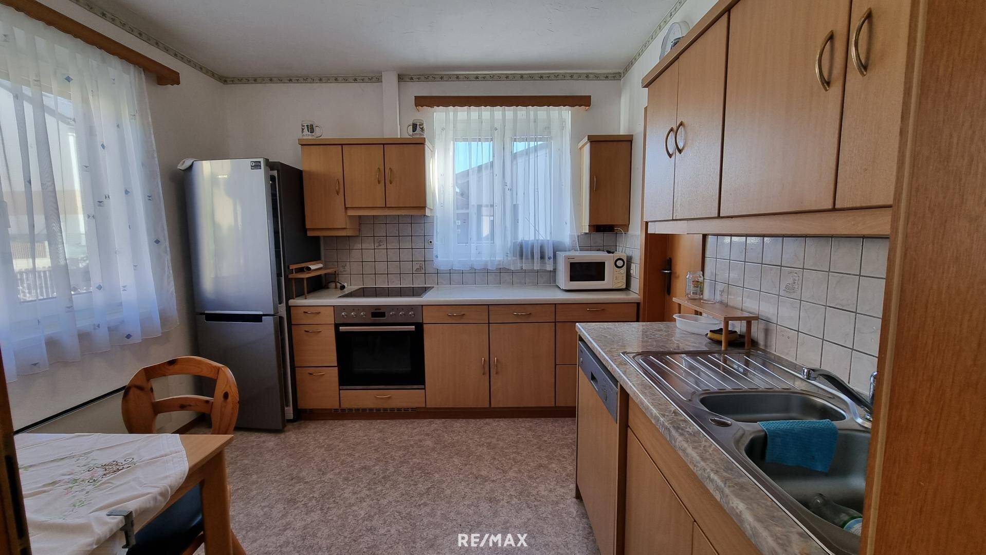 Funktionale Küche mit Holzschränken, Fliesenrückwand und Essbereich.