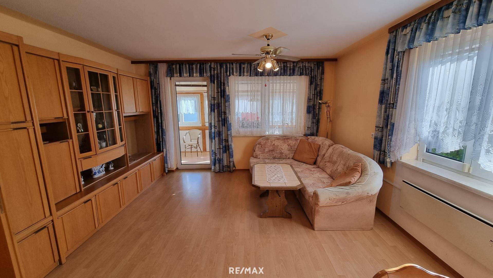 Gemütliches Wohnzimmer mit Holzmöbeln, Sofa und Zugang zum Wintergarten.