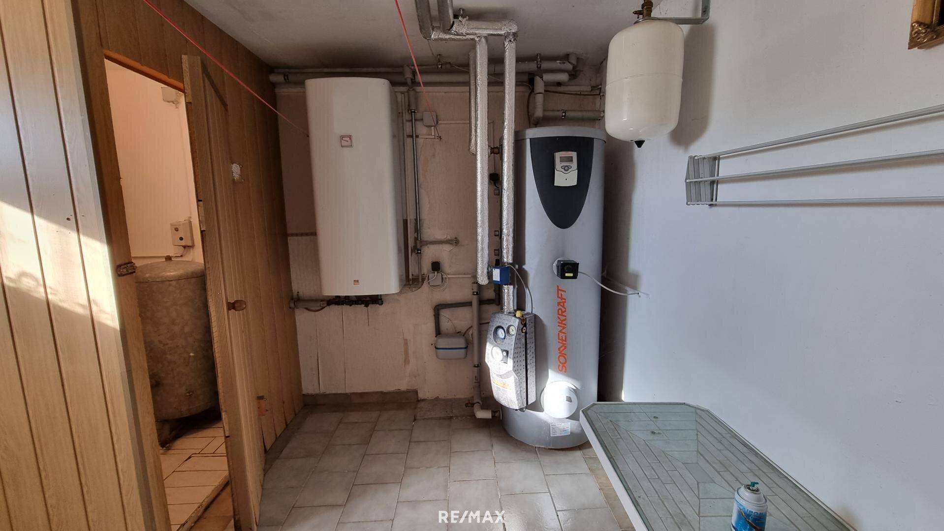 Heizungsraum im Keller mit Warmwasserspeicher und technischen Installationen.