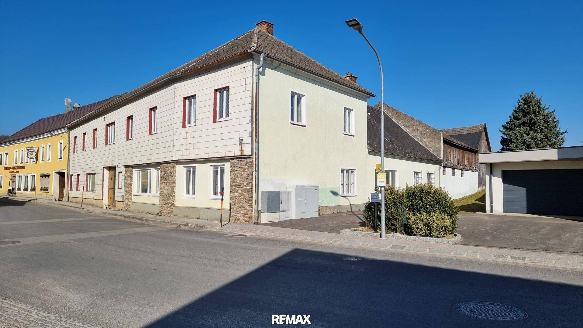 Straßenansicht eines historischen Gebäudes mit hellgelber Fassade, weißen Fenstern und einer Garage.