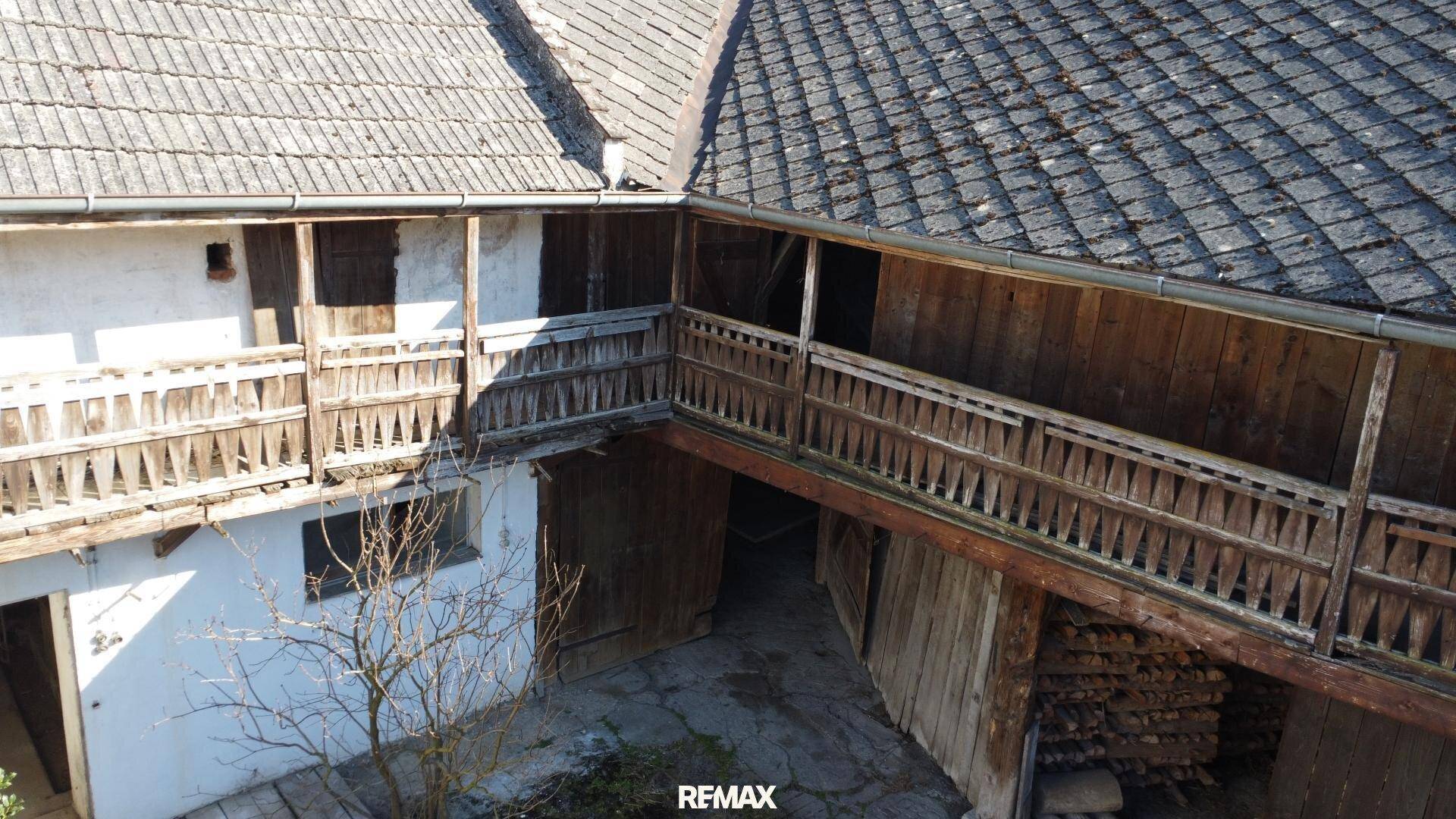 Blick von oben auf einen Innenhof, umgeben von alten Gebäuden mit Holzbalkonen und traditionellen Dächern.