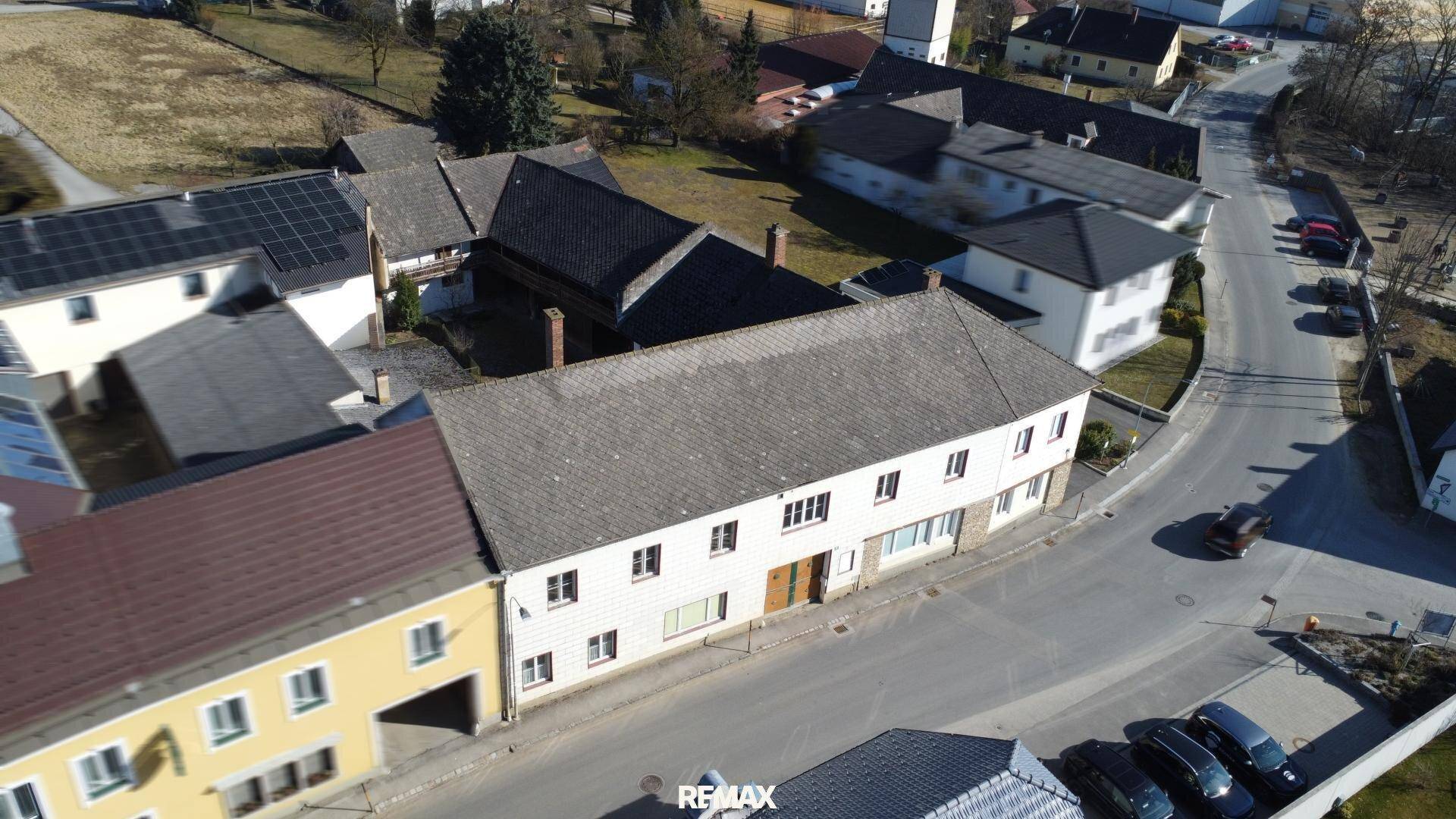 Luftaufnahme eines ländlichen Anwesens mit mehreren Gebäuden und Dächern in einer kleinen Siedlung.